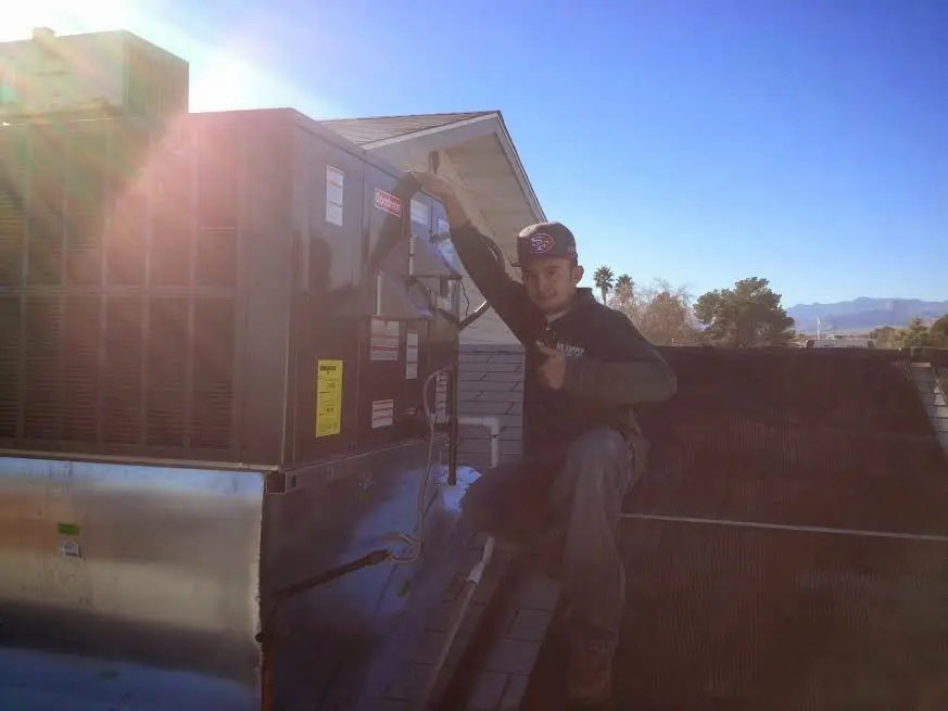 HVAC technician performing AC Tune-Up on a rooftop unit in Odenville